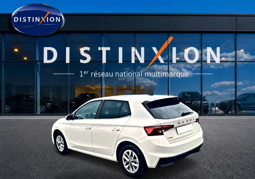 Vue 3/4 arrière droite d'une Skoda Fabia blanche 2025 devant une vitrine Distinxion, avec jantes alu et feux LED.