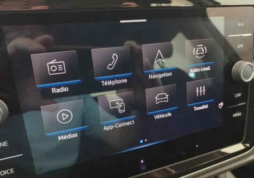 Écran tactile central du Volkswagen Touran 2024 affichant les menus radio, téléphone, navigation et aides à la conduite.