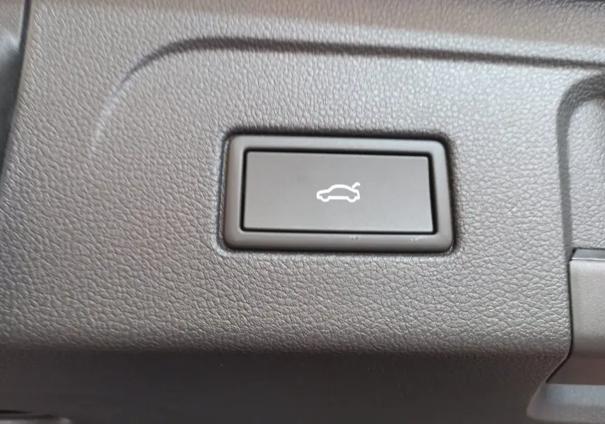 Gros plan sur le bouton d'ouverture électrique du coffre dans l'habitacle noir du Volkswagen Touran 2024.