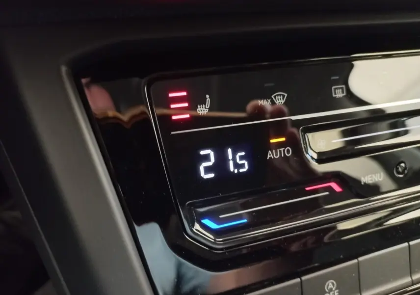 Gros plan sur la commande de climatisation digitale avec affichage de 21,5°C dans un Volkswagen Touran noir 2024.