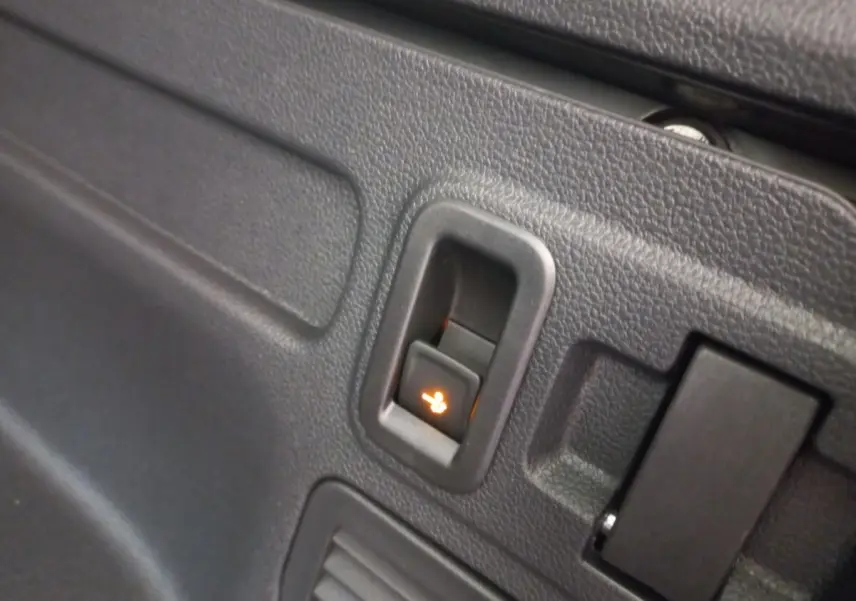Détail du bouton de rabattement électrique des sièges arrière sur la garniture intérieure noire du Volkswagen Touran 2024.