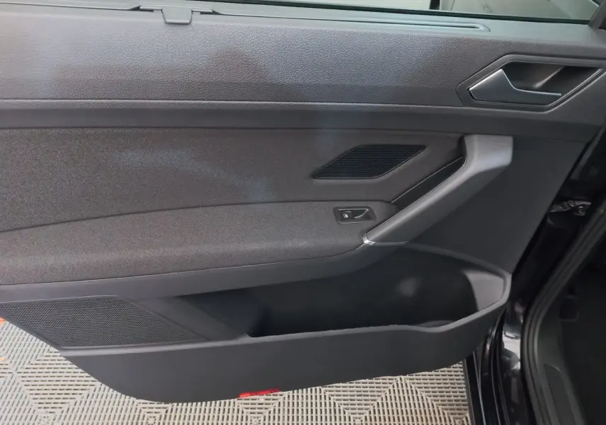 Vue rapprochée de la porte intérieure côté droit noire du Volkswagen Touran 2024 avec poignée argentée et commande de verrouillage.