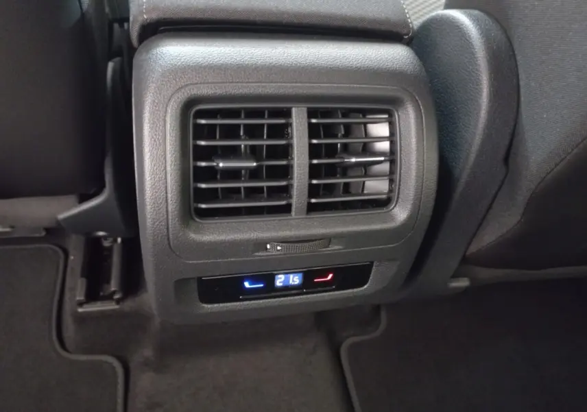 Vue rapprochée des bouches d'aération arrière et commande de climatisation digitale dans un Volkswagen Touran noir 2024.