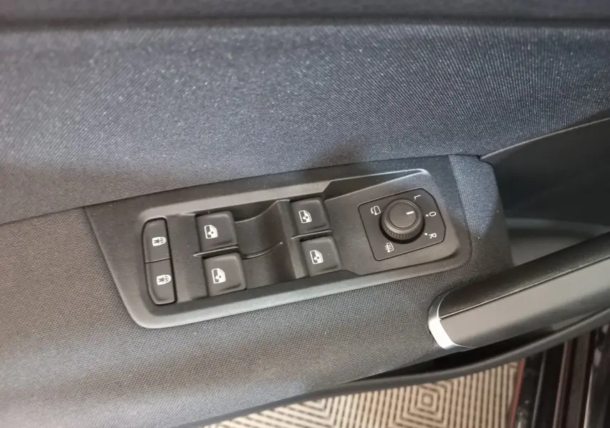 Détail des commandes de lève-vitres et rétroviseurs sur la porte côté conducteur d’un Volkswagen Touran noir 2024.