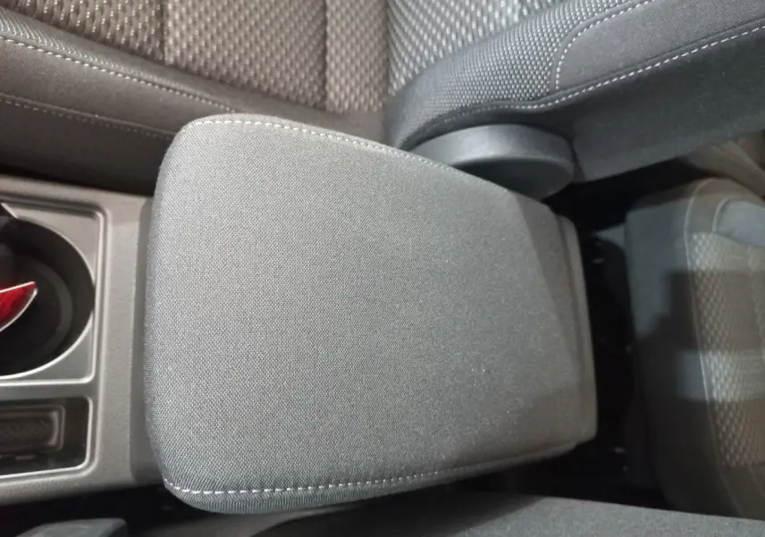 Détail de l'accoudoir central en tissu gris dans l'habitacle du Volkswagen Touran 2024, vue de dessus.