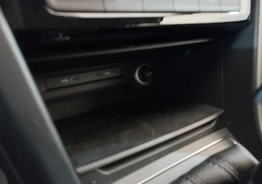 Gros plan sur la console centrale noire du Volkswagen Touran 2024, montrant les ports USB et prise 12V.