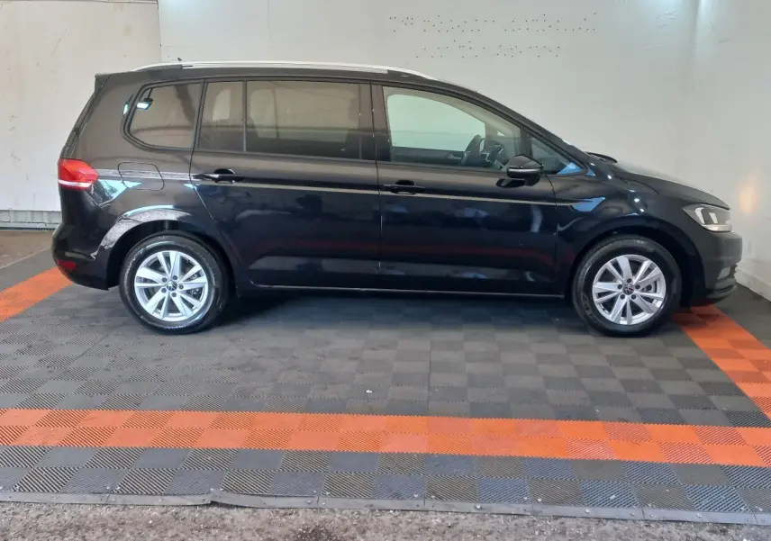 Vue de profil côté gauche d'un Volkswagen Touran noir 2024, avec jantes alliage et vitres teintées.