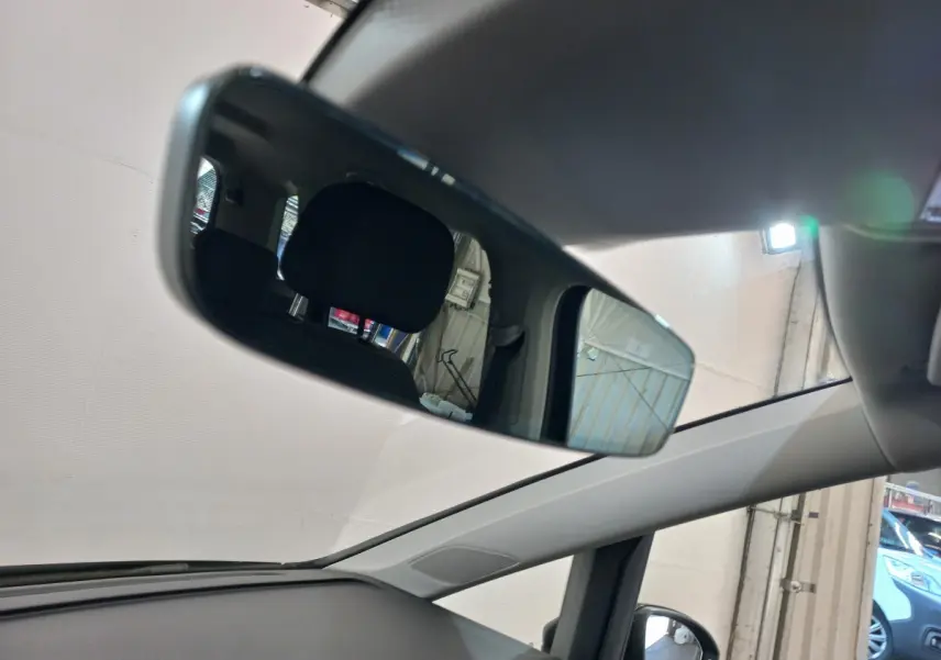 Vue intérieure du rétroviseur central du Volkswagen Touran noir 2024, montrant l'arrière des sièges et une partie du toit ouvrant.