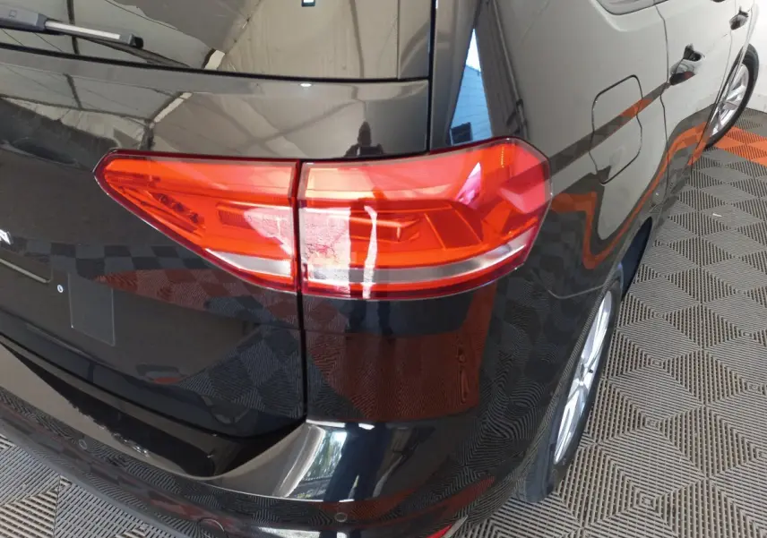 Vue arrière côté droit du Volkswagen Touran noir 2024, mettant en valeur le feu arrière et la carrosserie brillante.