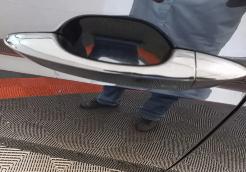 Poignée de porte chromée en gros plan sur la porte côté droit d’un Volkswagen Touran noir 2024.