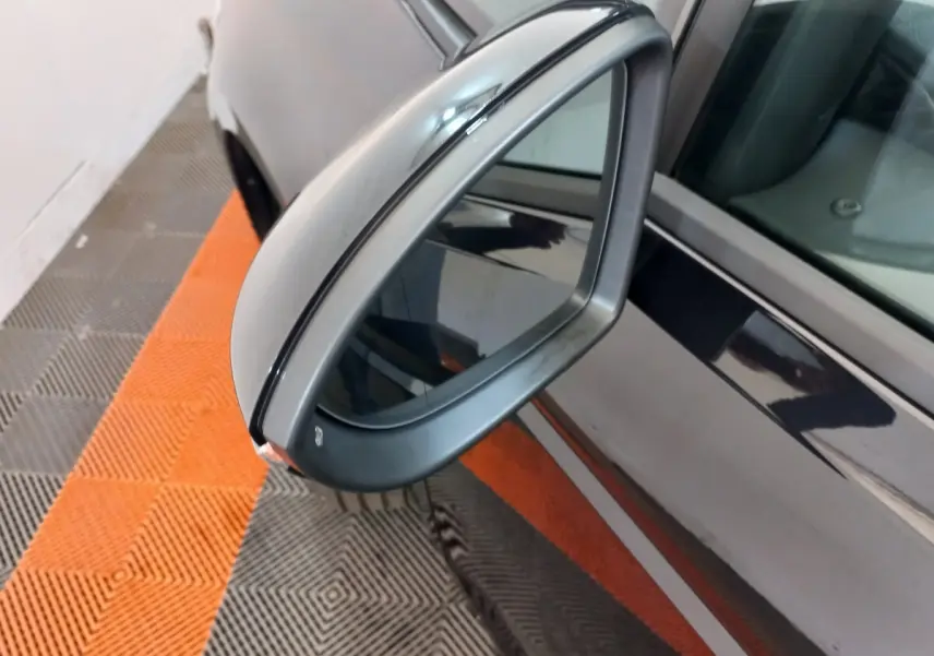 Rétroviseur côté gauche gris métallisé du Volkswagen Touran noir, vue rapprochée avec reflet sur la portière.