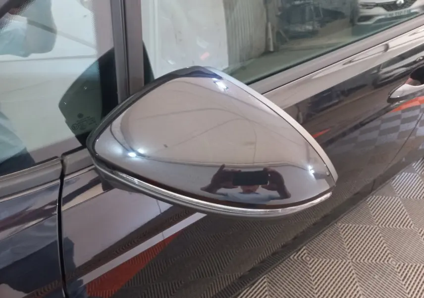 Rétroviseur côté gauche noir brillant du Volkswagen Touran 2024 avec clignotant intégré, vue rapprochée en intérieur.