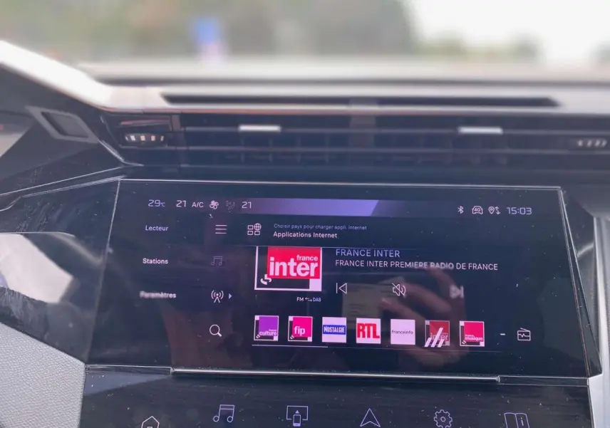 Écran tactile central de la Peugeot 308 2023 affichant les stations radio, vue intérieure frontale.