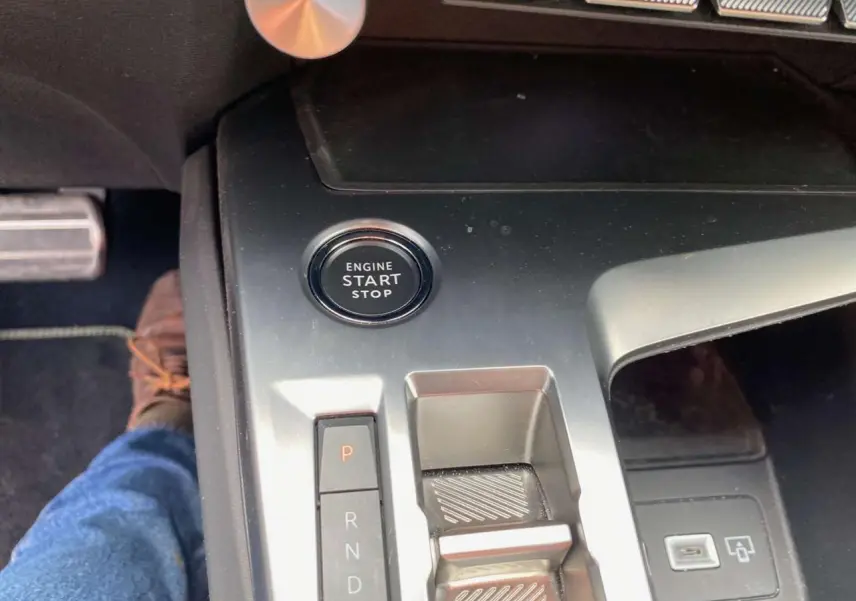 Gros plan sur la console centrale de la Peugeot 308 2023 avec bouton start/stop et levier de boîte automatique.