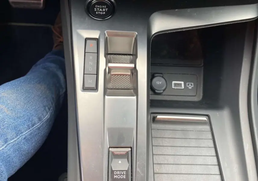 Vue rapprochée de la console centrale de la Peugeot 308 2023, avec levier de boîte auto et bouton start/stop.