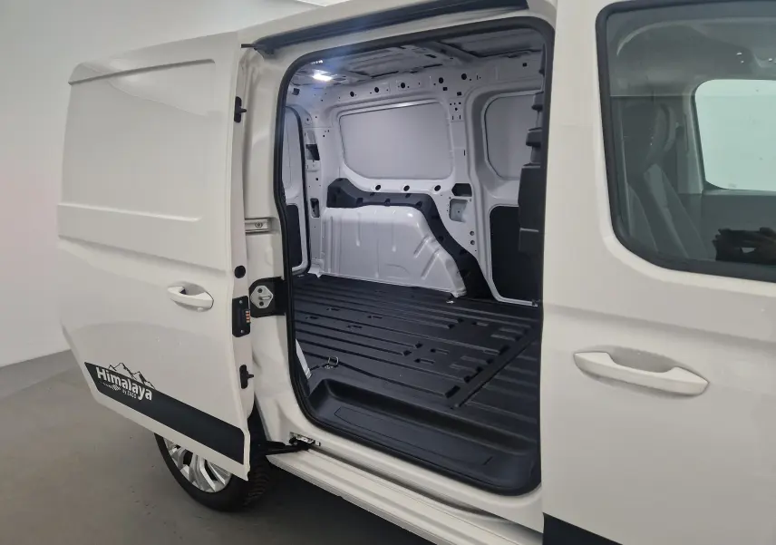 Vue latérale gauche du Volkswagen Caddy Maxi blanc avec porte coulissante ouverte montrant l'espace de chargement vide et le logo Himalaya.