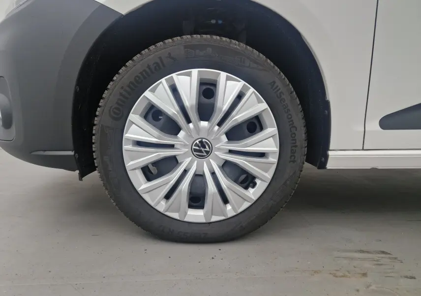 Gros plan sur la roue avant gauche blanche du Volkswagen Caddy Maxi 2025 avec jante argentée et pneu Continental.