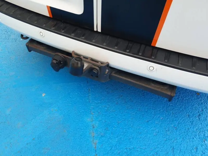 Gros plan sur le crochet d'attelage arrière du Ford Transit Custom blanc Glacier, avec caméra de recul visible sur le pare-chocs.