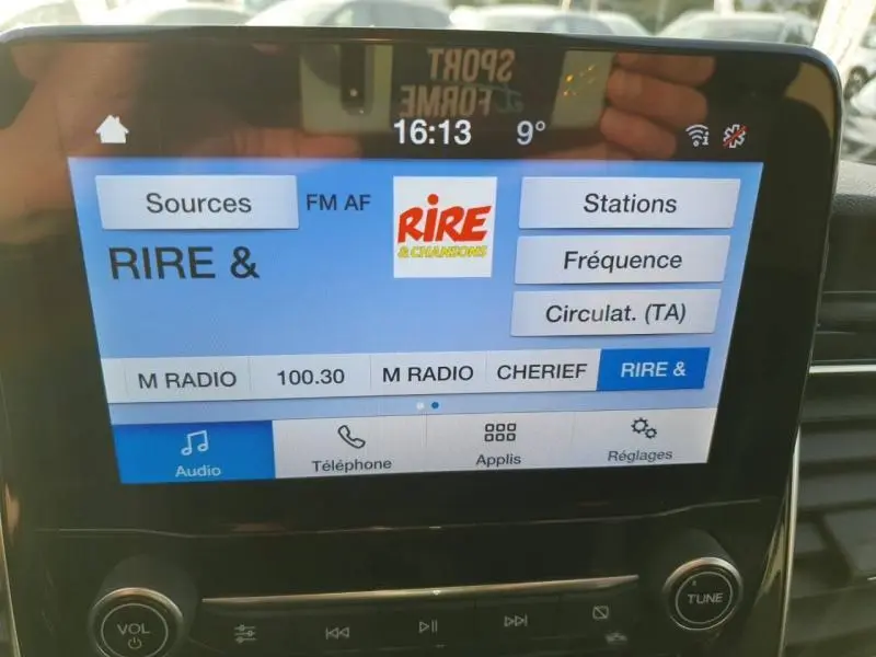 Écran tactile central du Ford Transit Custom blanc, affichant la radio FM sur la station RIRE & CHANSONS.