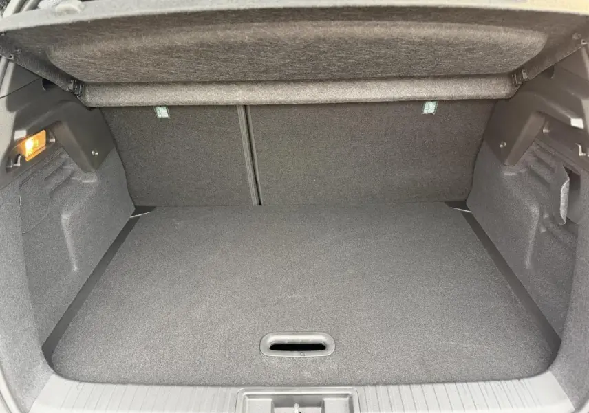 Coffre spacieux du Renault Captur 2025 en vue intérieure, avec revêtement gris foncé et éclairage latéral.