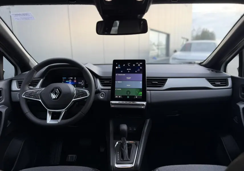 Vue intérieure frontale du tableau de bord du Renault Captur blanc nacré, avec écran tactile vertical et volant multifonction.