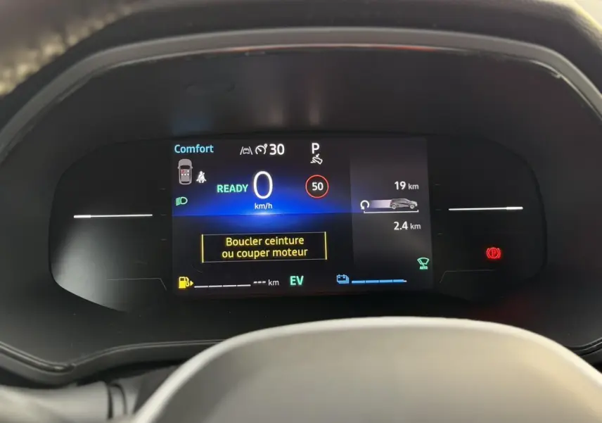 Tableau de bord numérique du Renault Captur hybride 2025 affichant la vitesse, alertes et mode confort, vue frontale rapprochée.