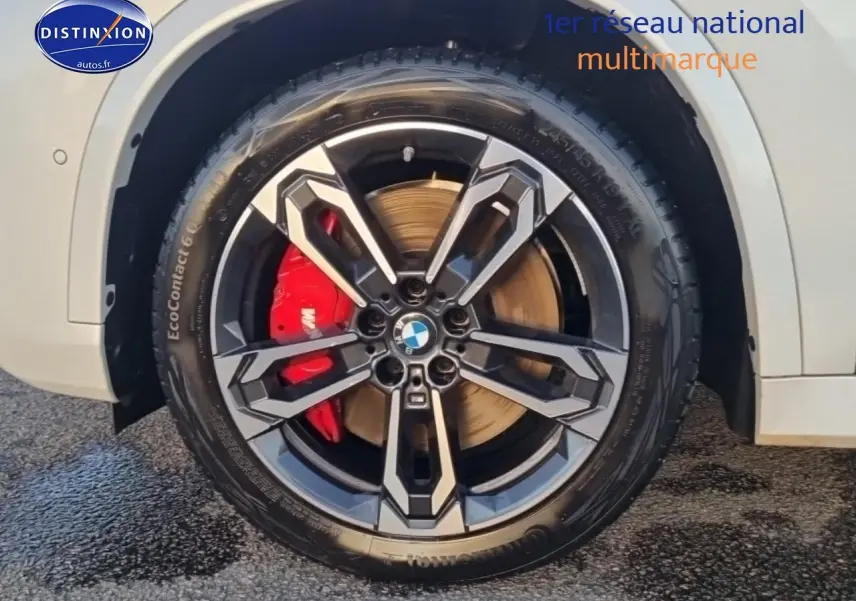 Gros plan sur la roue avant droite blanche d'une BMW X1 2025 avec jante alliage bicolore et étrier de frein rouge.