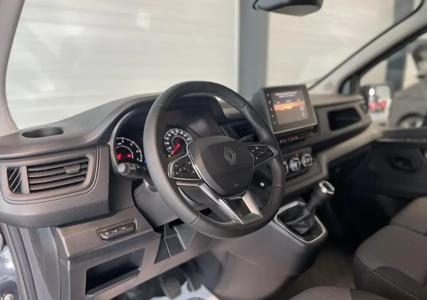 Vue intérieure côté conducteur du Renault Trafic Fourgon gris Comète, avec volant multifonction et écran tactile central.
