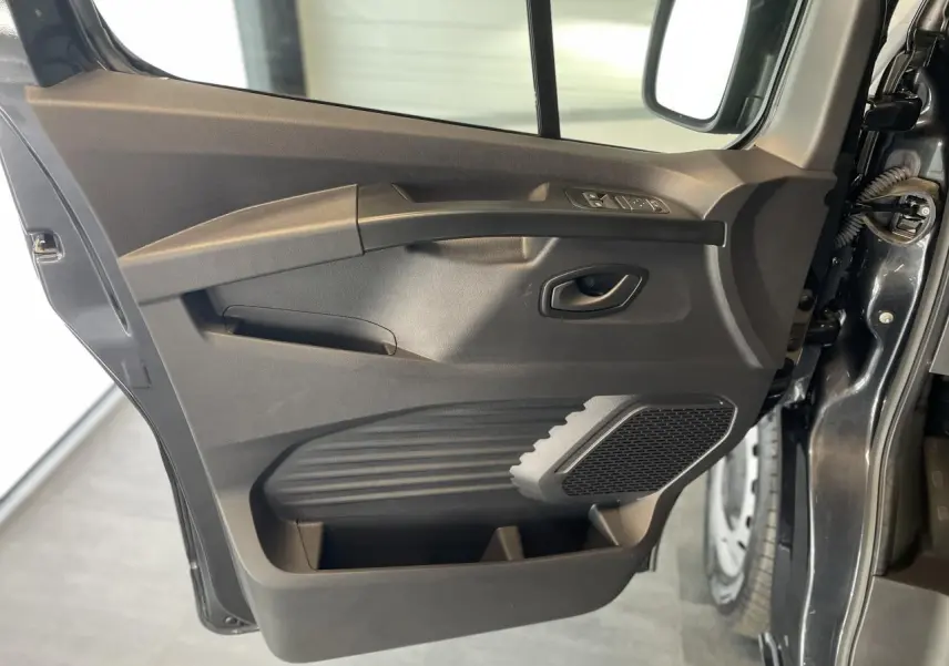 Vue intérieure de la porte avant gauche gris comète du Renault Trafic Fourgon avec commandes de vitres et haut-parleur intégré.