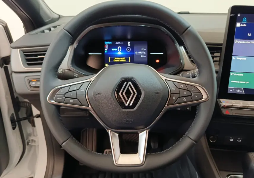 Vue frontale du volant cuir noir avec commandes multifonctions du Renault Captur Techno E-Tech 145 blanc, tableau de bord numérique.