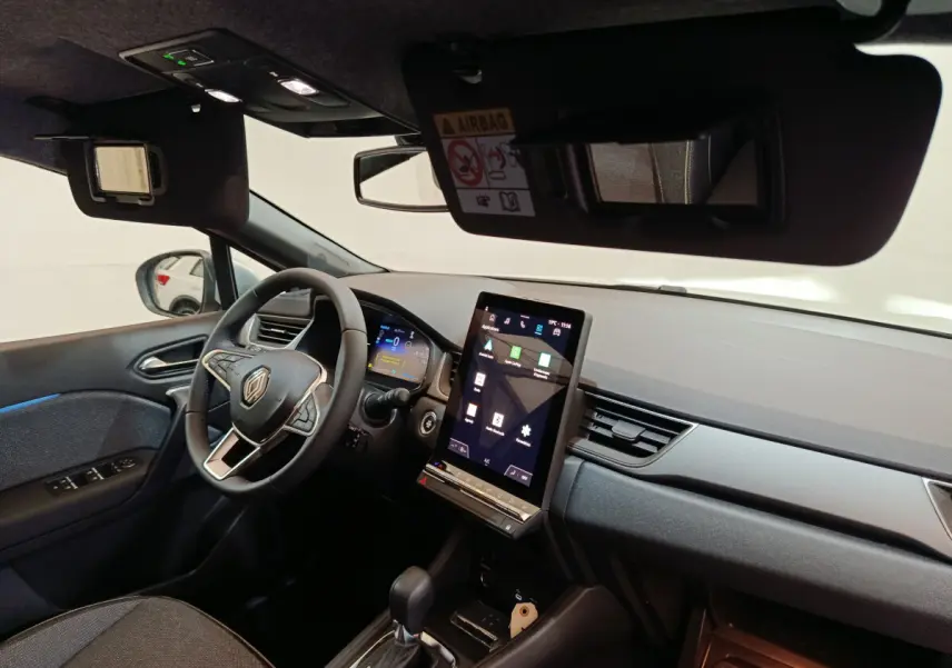 Vue intérieure côté conducteur du tableau de bord noir du Renault Captur blanc avec écran tactile vertical et volant multifonctions.