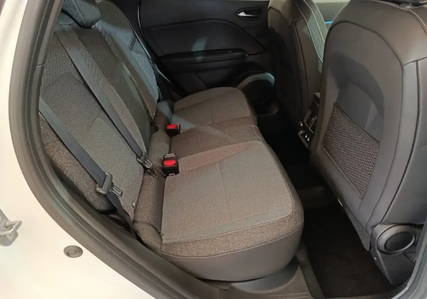 Vue latérale intérieure du siège arrière gris du Renault Captur blanc, avec ceintures de sécurité et dossier avant en cuir noir.