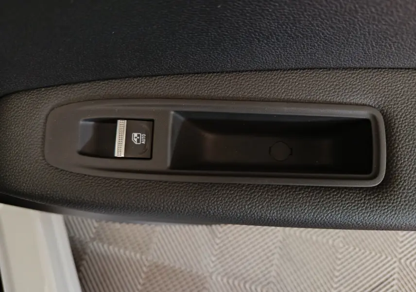 Gros plan sur le bouton de commande de la vitre électrique côté gauche d’un Renault Captur blanc 2025.