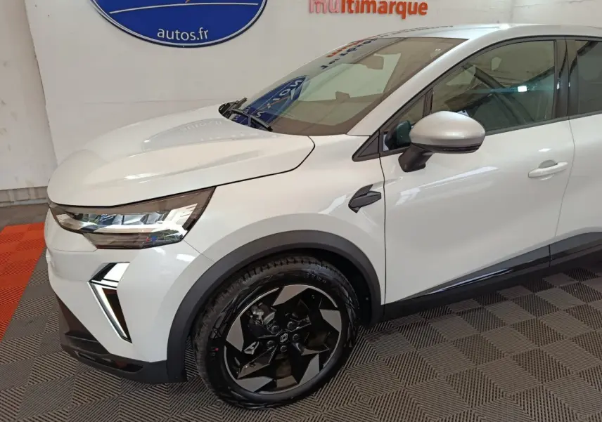 Vue 3/4 avant droit du Renault Captur blanc 2025 avec jantes noires et phares LED distinctifs.