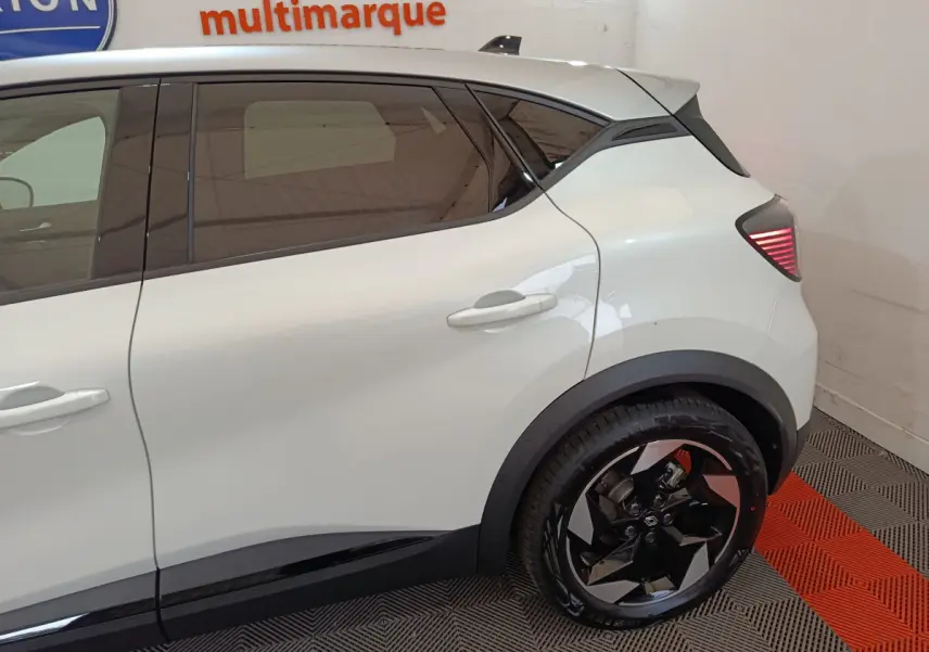 Vue côté droit arrière du Renault Captur blanc 2025, mettant en valeur la porte arrière et la roue au design moderne.