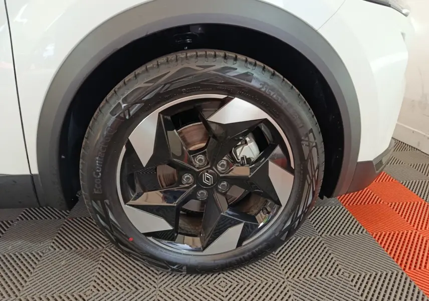 Gros plan sur la roue avant droite du Renault Captur blanc 2025, mettant en valeur la jante noire et argentée au design géométrique.