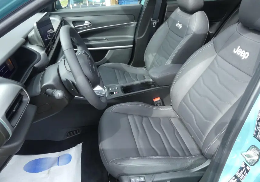 Vue intérieure côté conducteur du Jeep Avenger 2024 bleu métallisé, sièges cuir noir avec logo Jeep brodé.