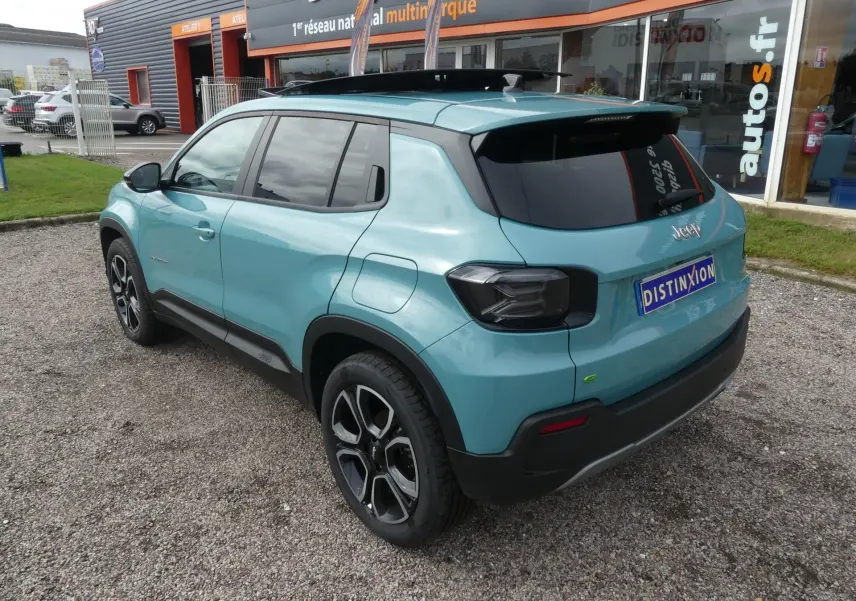 Vue 3/4 arrière droite d'un Jeep Avenger bleu métallisé avec toit noir et vitres arrière surteintées.