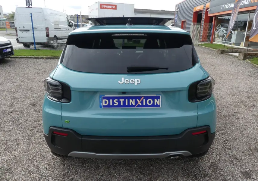 Vue arrière d'un Jeep Avenger bleu métallisé avec feux arrière fumés et plaque d'immatriculation Distinxion.