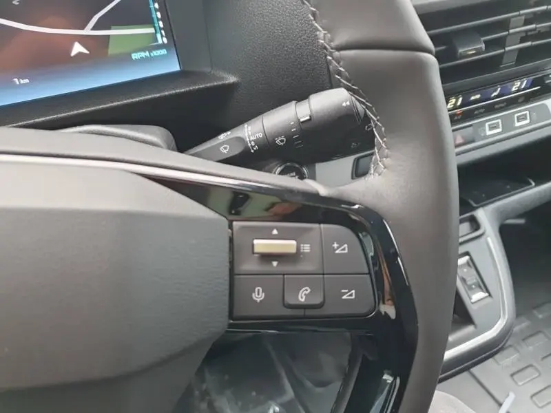 Gros plan sur les commandes au volant cuir noir du Citroën Jumpy gris Titane, avec écran tactile et tableau de bord partiel visible.