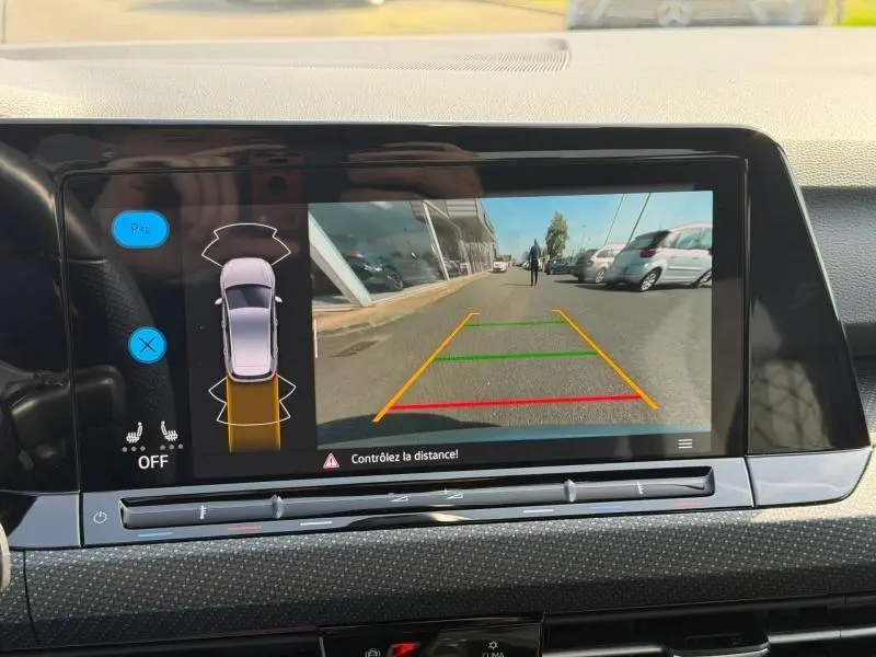 Vue de l'écran de caméra de recul du Volkswagen Golf 1.5 eTSI R-Line 2024, affichant la zone arrière avec lignes de guidage colorées.