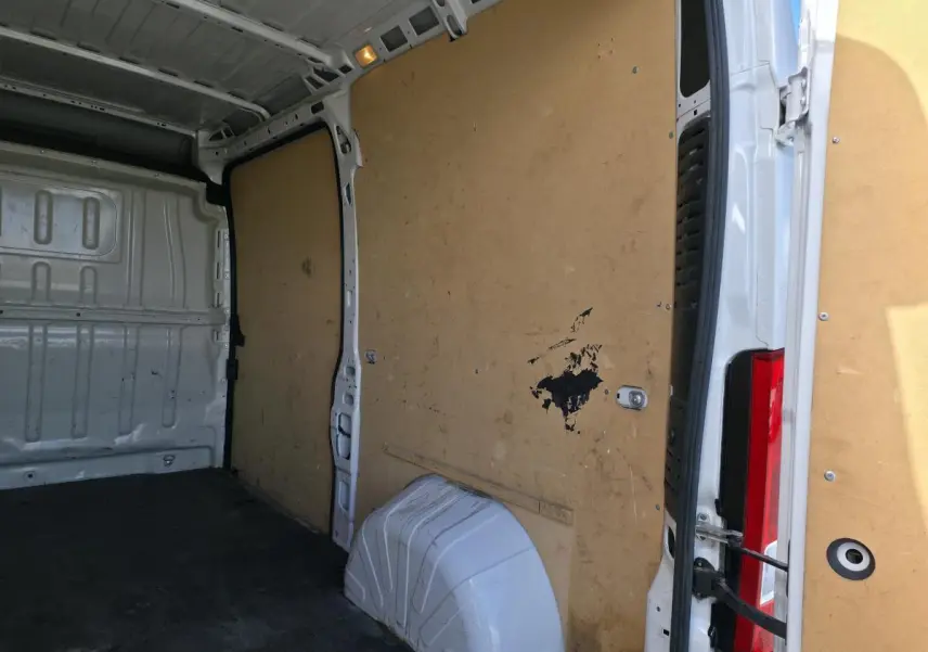 Intérieur du fourgon Opel Movano blanc, vue depuis l'arrière droit avec cloison en bois et plancher noir.