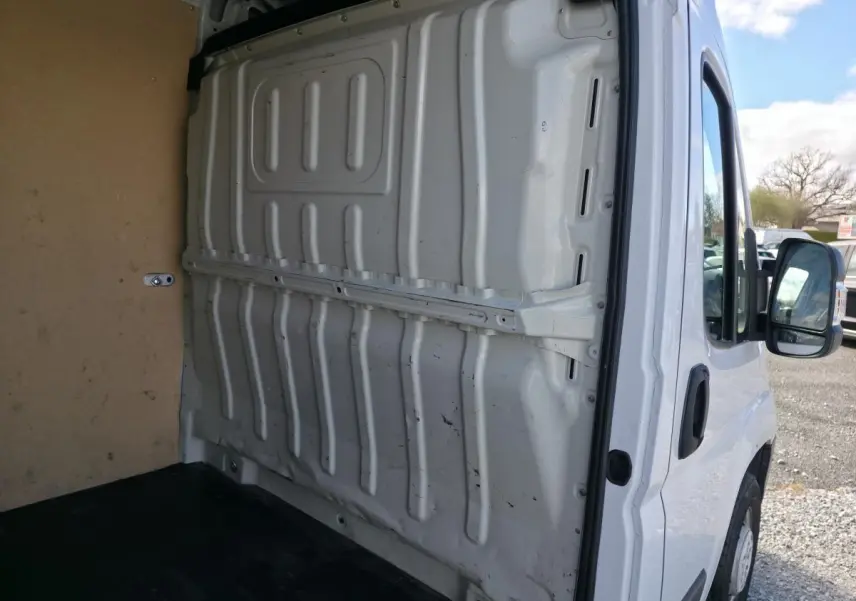 Vue intérieure arrière du fourgon blanc Opel Movano 2022, montrant la cloison pleine tôlée et le plancher noir.