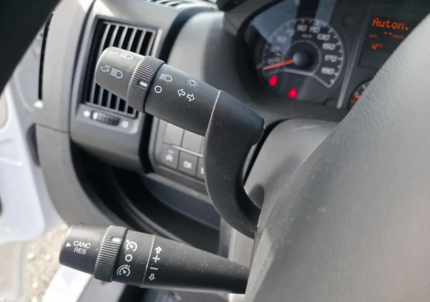 Gros plan sur les commandes au volant du côté gauche de l’Opel Movano Fourgon blanc, tableau de bord partiellement visible.