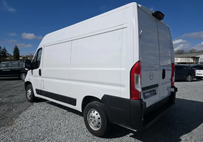Opel Movano Fourgon blanc vu en 3/4 arrière droit, portes arrière battantes et porte latérale droite tôlée visibles.