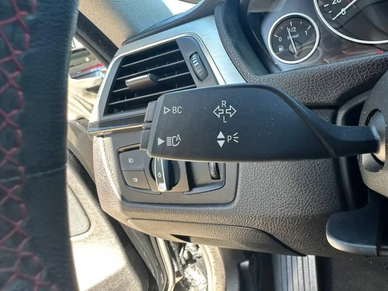 Gros plan sur la commande de clignotants et les commandes d'éclairage côté gauche du tableau de bord noir d'une BMW Série 4 Gran Coupe F36.