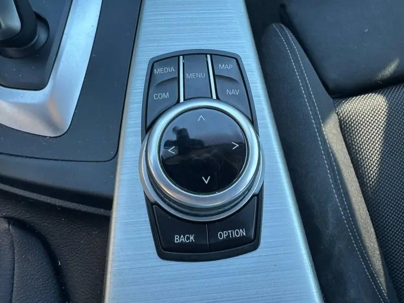 Gros plan sur la molette de commande iDrive au centre console de la BMW Série 4 Gran Coupe noire, finition Sport.