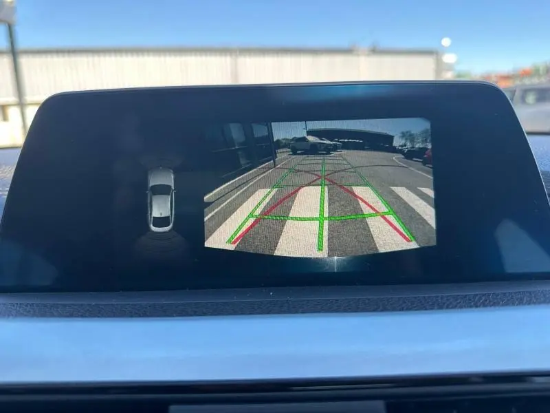 Écran de caméra de recul dans BMW Série 4 Gran Coupe noir, affichant vue arrière avec lignes de guidage vertes et rouges.
