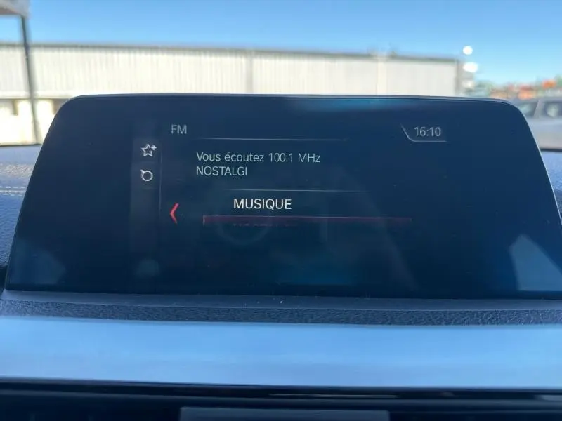 Écran multifonction couleur de la BMW Série 4 Gran Coupe F36 noir, affichant la radio FM sur 100.1 MHz Nostalgie.