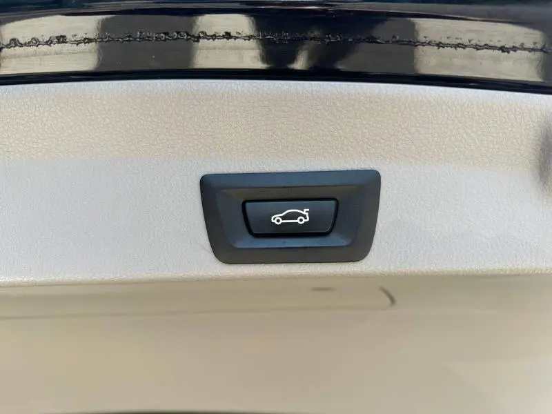 Bouton noir d'ouverture électrique du coffre sur la partie intérieure d'une BMW Série 4 Gran Coupe F36 noire.